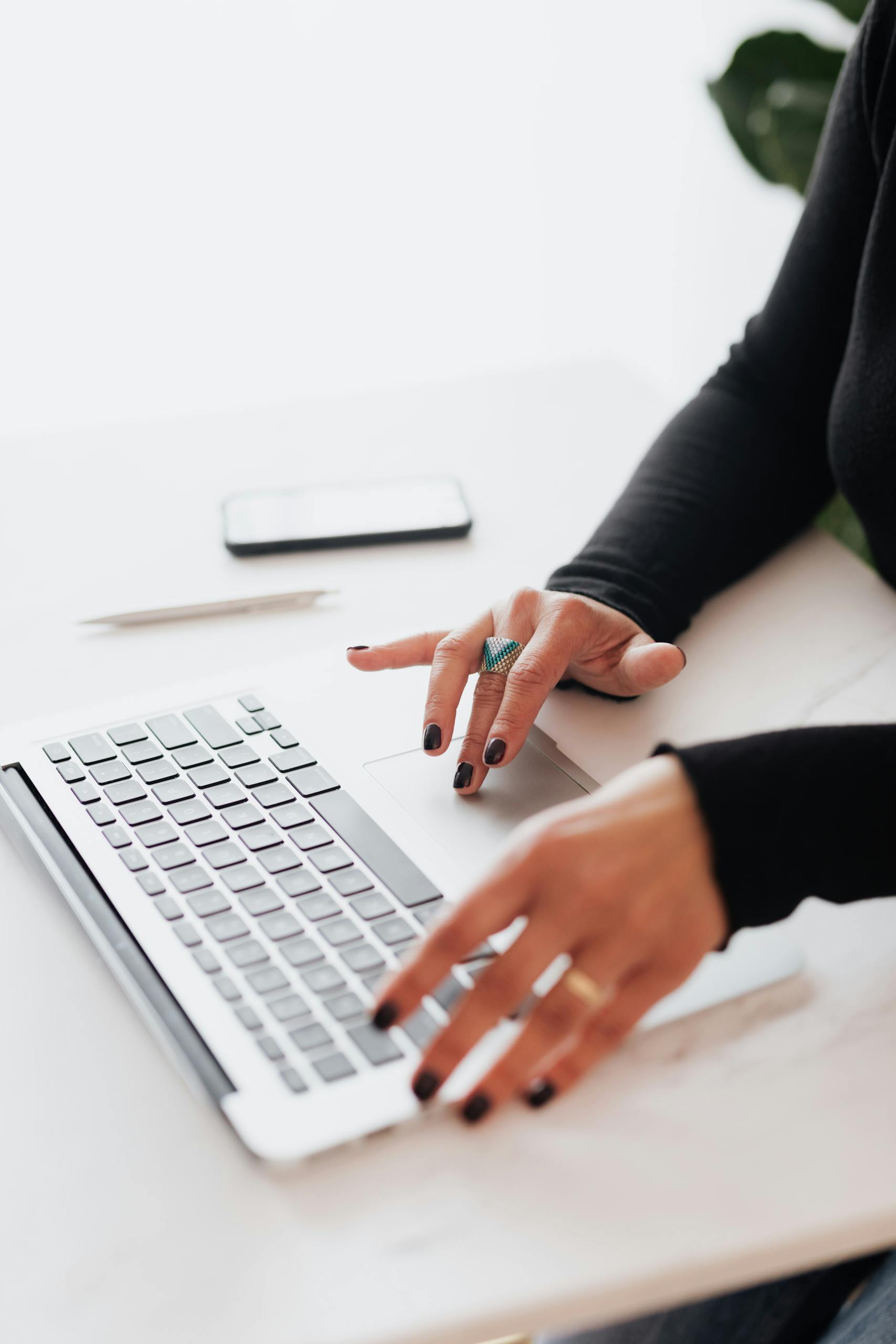 Crop female using touchpad on laptop in office